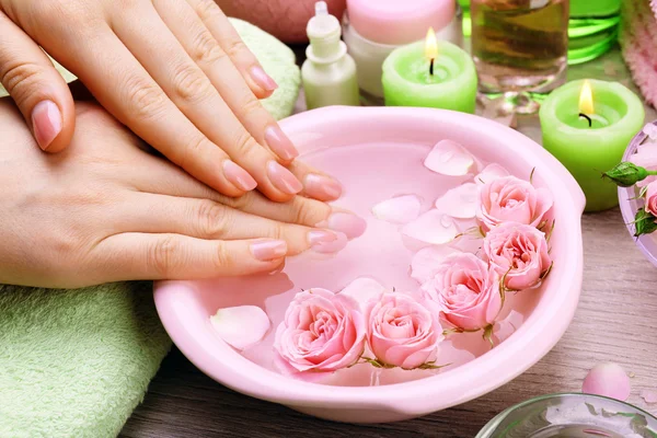 Mãos femininas com tigela de água de spa de aroma em mesa de madeira, close-up — Fotografia de Stock