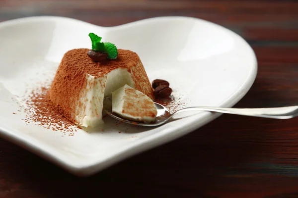 Вкусный десерт из панны на тарелке, на деревянном столе — стоковое фото