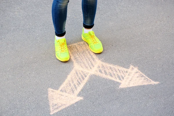 Female feet and drawing arrows on pavement background — Stock Photo, Image