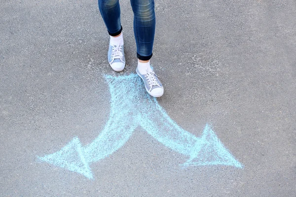 Vrouwelijke voeten en tekening pijlen op stoep achtergrond — Stockfoto