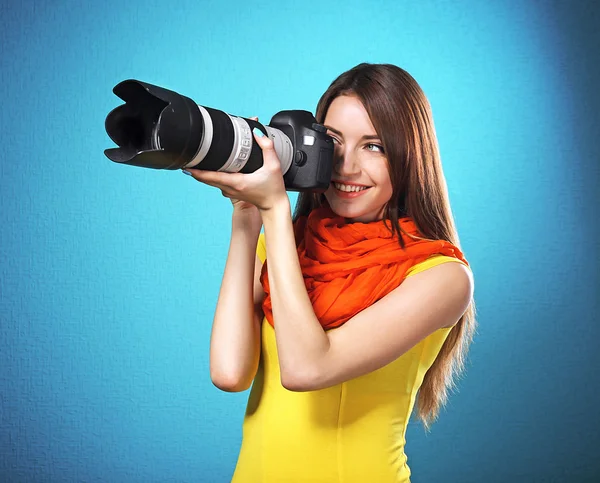 Młoda kobieta fotograf robienia zdjęć na niebieskim tle — Zdjęcie stockowe