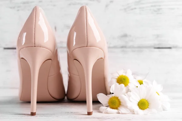 Ženské boty s květinami na dřevěné pozadí — Stock fotografie