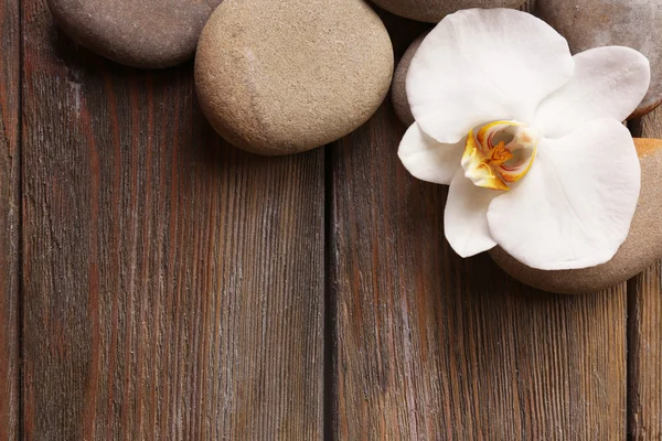Spa stenen en orchideebloem op houten achtergrond — Stockfoto