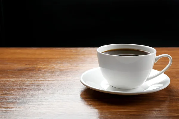 Cup of coffee on table on dark background — Stock Photo, Image