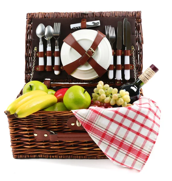 Rieten picknickmand met eten, vaatwerk en geïsoleerd op wit tafellaken — Stockfoto