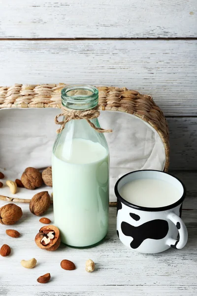 Milk in glassware and walnuts on wooden background — Stock Photo, Image