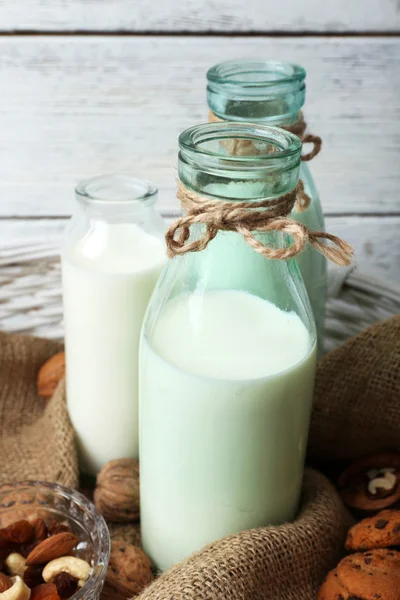 Leche en cristalería con nueces y galletas sobre fondo de madera — Foto de Stock