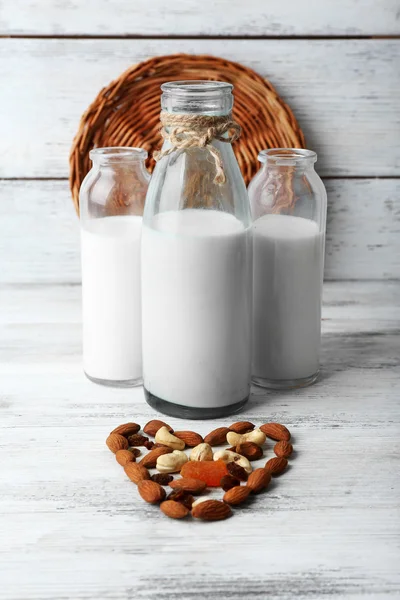 Leche en cristalería y nueces sobre fondo de madera —  Fotos de Stock