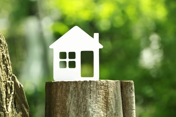 Small model of house on stump on green blurred background — Stock Photo, Image