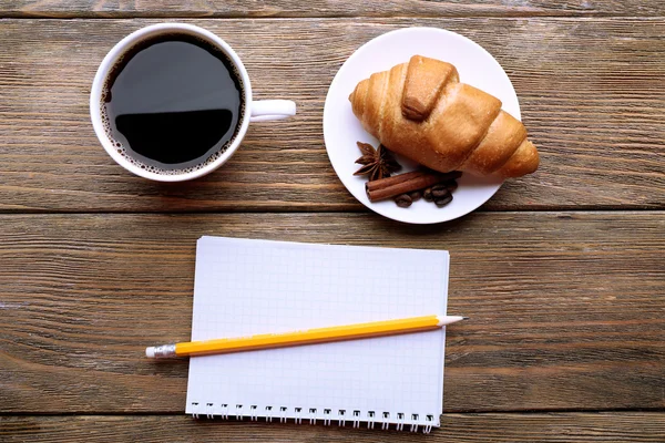 Kávét és friss croissant-t üres papírlapot a fából készült asztal, felülnézet — Stock Fotó