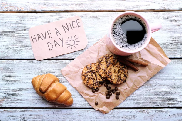 Cup of coffee with fresh croissant and Have A Nice Day massage on wooden table, top view — Stock Photo, Image