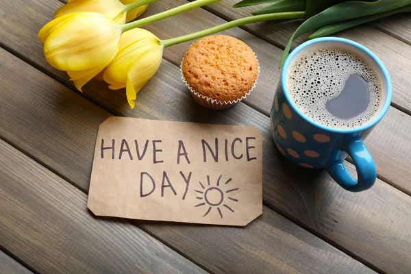 Kopp kaffe med färska cupcake, tulpaner och Have A Nice Day massage på trä bakgrund — Stockfoto