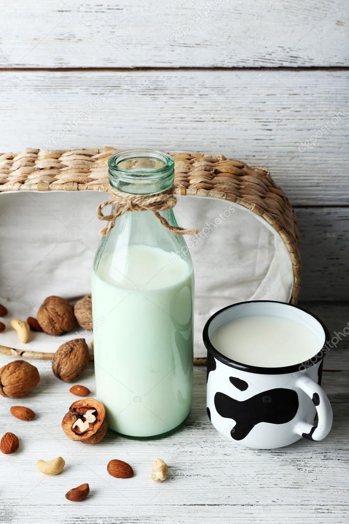 Milk in glassware and walnuts on wooden background