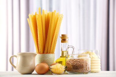 Zeytinyağı, yumurta, peynir ve perde arka plan üzerinde ahşap masa üzerinde un ile makarna