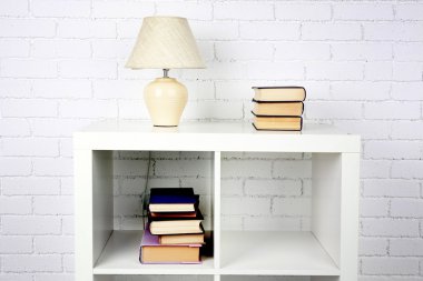 Kitap ve tuğla duvar arka lamba ile ahşap raf