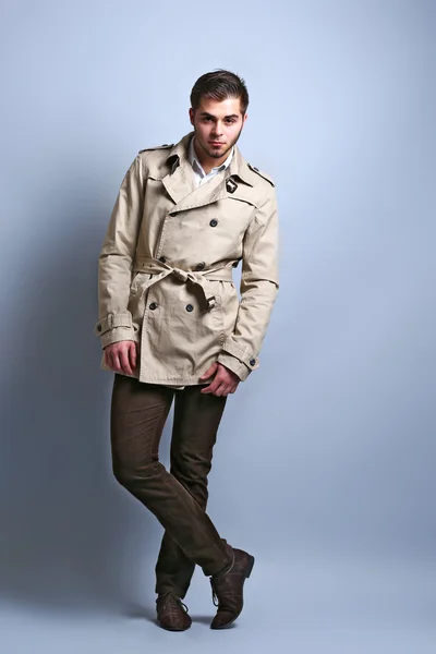 Jeune homme en manteau sur fond gris — Photo