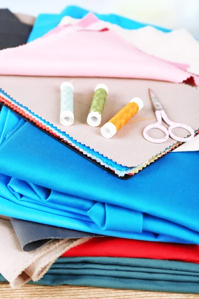 Colorful fabric samples. threads and scissors on table and light blurred background — Stock Photo, Image