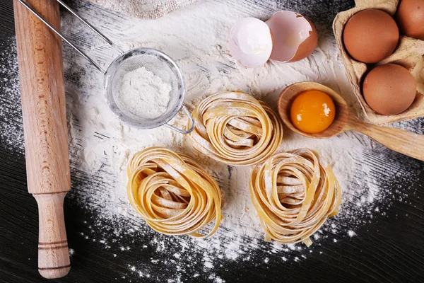 Pasta casera cruda e ingredientes para pasta sobre fondo de madera —  Fotos de Stock