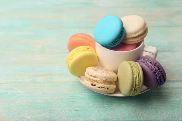 Macaroons coloridos saborosos na cor de fundo de madeira — Fotografia de Stock