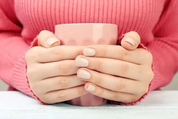 Female hands holding cup of coffee on wooden table close up — Stock Photo, Image