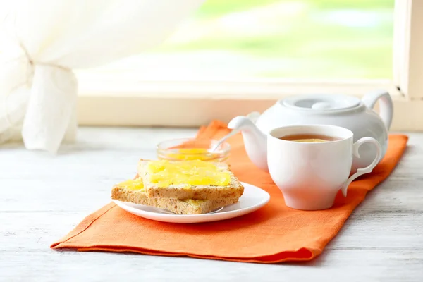 Toasts with honey on plate and cup of tea on light background — Stock Photo, Image
