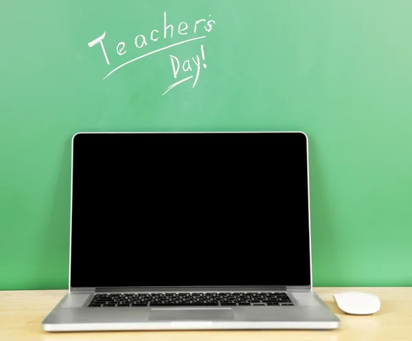 Laptop on table, on green blackboard background — Stock Photo, Image