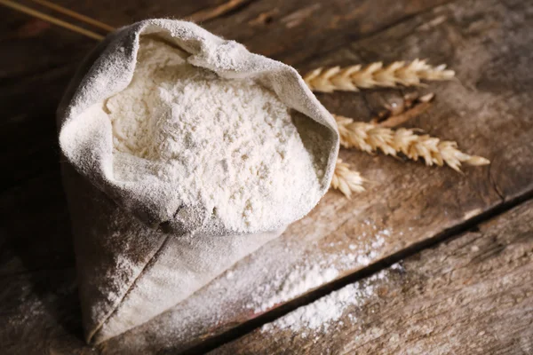 木製の背景に小麦の耳と白い小麦粉の袋 — ストック写真