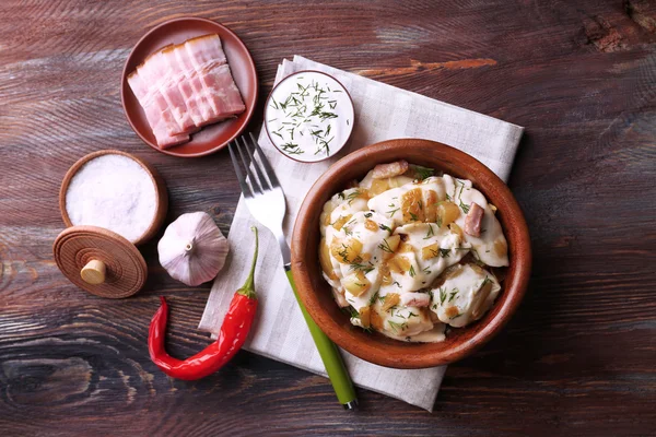Gefrituurde dumplings met ajuin en spek in koekenpan, op houten tafel achtergrond — Stockfoto