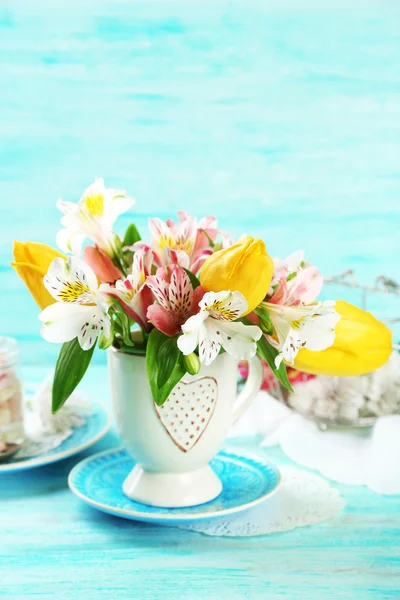 Красивые цветы в чашке, на цветном деревянном фоне — стоковое фото