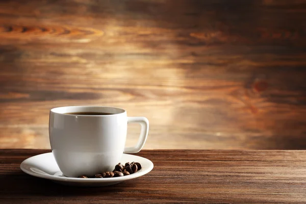 Xícara de café com grãos em fundo de madeira — Fotografia de Stock