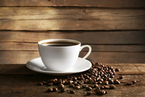 Tazza di caffè con chicchi su sfondo di legno — Foto Stock