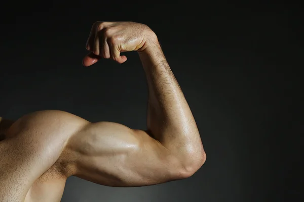 Brazo muscular flexionado sobre fondo oscuro —  Fotos de Stock