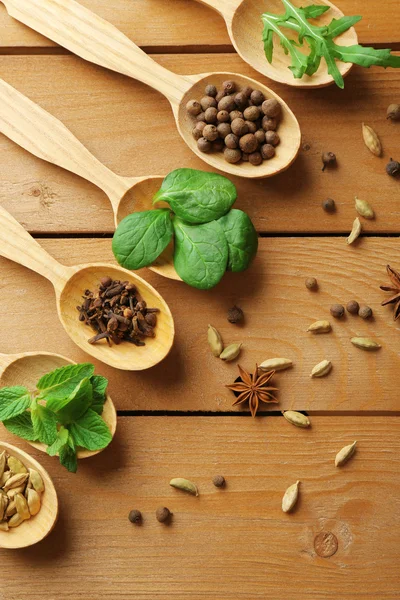 Wooden spoons with fresh herbs and spices on wooden background — Stock Photo, Image