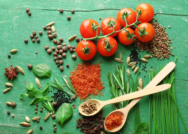 Tomatoes with wooden spoons with fresh herbs and spices on wooden background — Stock Photo, Image