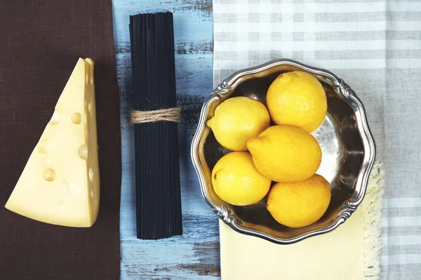 Sýr, černé špagety a citrony na dřevěný stůl horní pohled — Stock fotografie