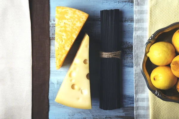 Fromage, spaghettis noirs et citrons sur table en bois vue sur le dessus — Photo