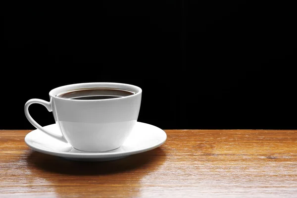 Cup of coffee on wooden table on black background — Stock Photo, Image