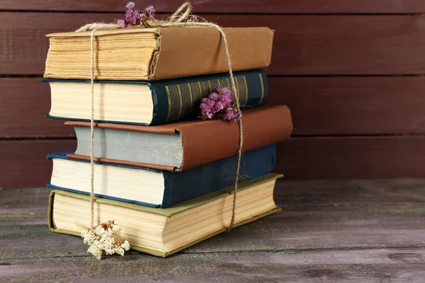 Stack of books with dry flowers on wooden background — Stock Photo, Image