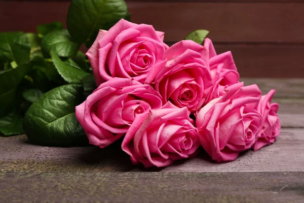 Hermosas rosas rosadas sobre fondo de madera — Foto de Stock