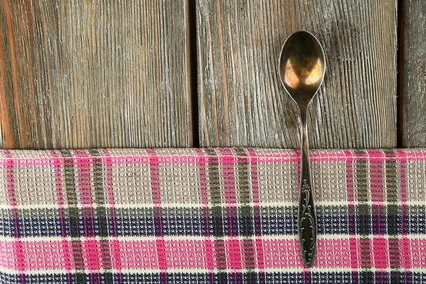 Checkered serwetka z łyżką na drewnianym stole tło — Zdjęcie stockowe