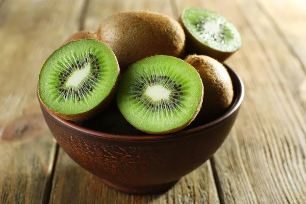 Juicy kiwi fruit in bowl on wooden background — Stock Photo, Image