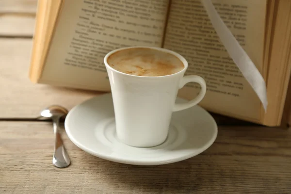 Stilleben med kopp kaffe och bok, på träbord — Stockfoto