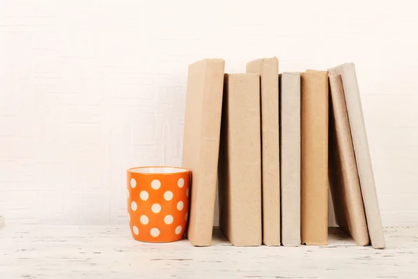 Böcker och cup på trähylla — Stockfoto