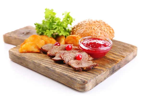 Beef with cranberry sauce, roasted potato slices and bun on wooden board, isolated on white — Stock Photo, Image