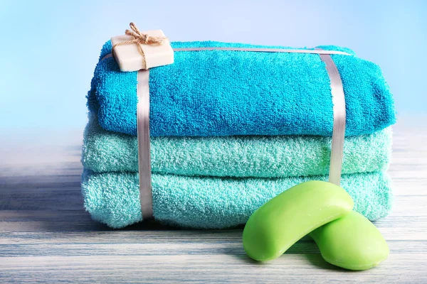 Still life with set of tied towels on wooden surface and light colorful background — Stock Photo, Image