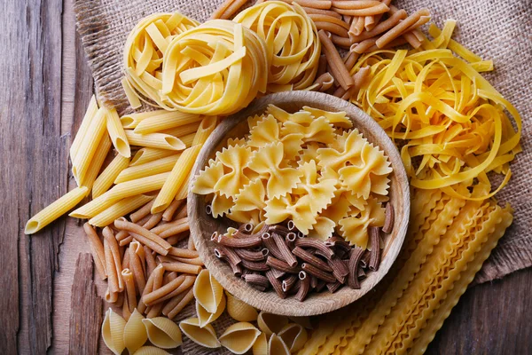 Different types of pasta on rustic wooden table — Stock Photo, Image