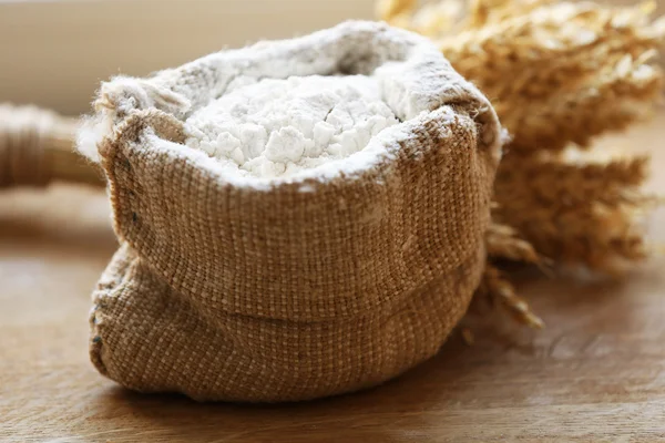 Flour in burlap bag on wooden background — Stock Photo, Image