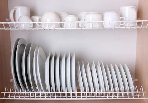 Clean dishes drying on metal dish rack on shelf — Stock Photo, Image