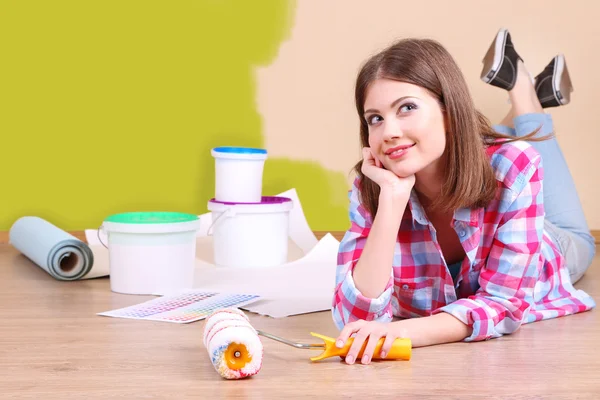 Schöne Mädchen auf dem Boden liegend mit Ausrüstung zum Bemalen der Wand — Stockfoto