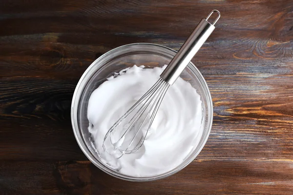 Schlageiweiß für Sahne auf Holztisch, Ansicht von oben — Stockfoto